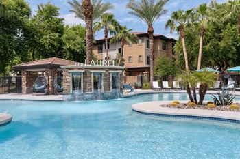 A pool with a waterfall and a building with the name Laurel on it. at The Laurel Apartments, Chandler, 85286